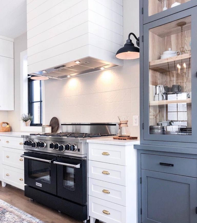 Kitchen with a slate blue built-in hutch, open shelving and warm brass hardware against white cabinetry