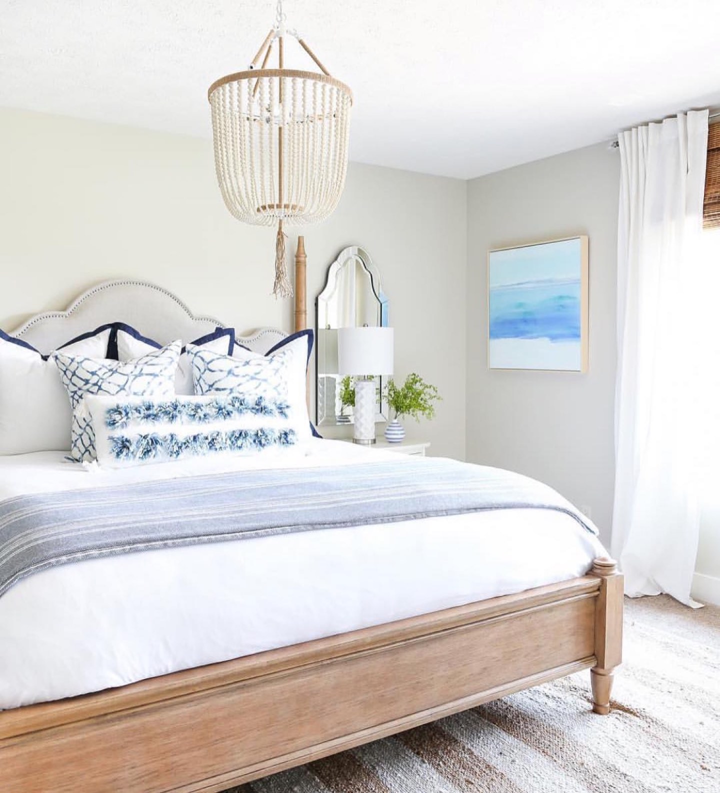 Coastal bedroom in indigo and white with layered bedding, natural textures and warm wood accents