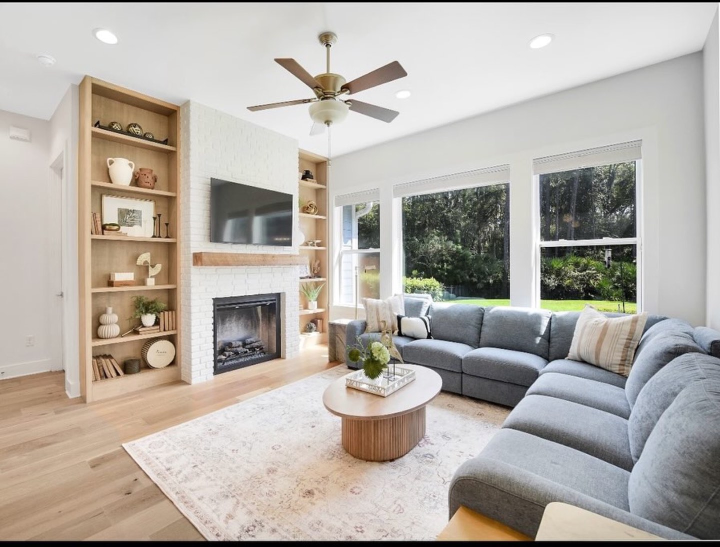 Living room with a white painted brick fireplace, built-in shelving and soft neutral furnishings